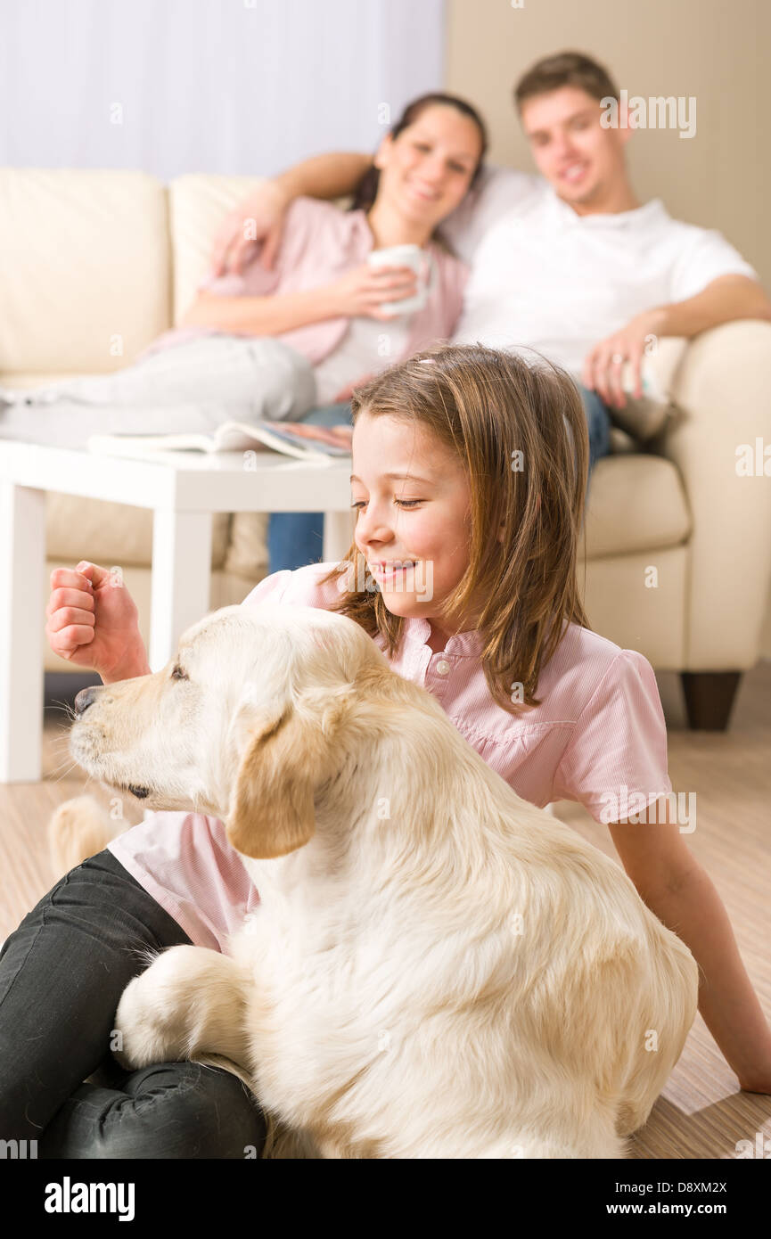 Giocoso ragazza petting cane di famiglia con i genitori seduti sul lettino Foto Stock