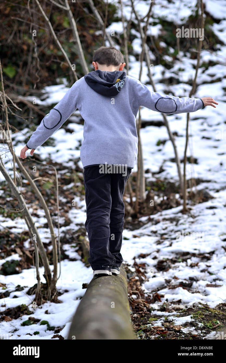 Un bambino a piedi attraverso un albero caduto attraverso i boschi Foto Stock