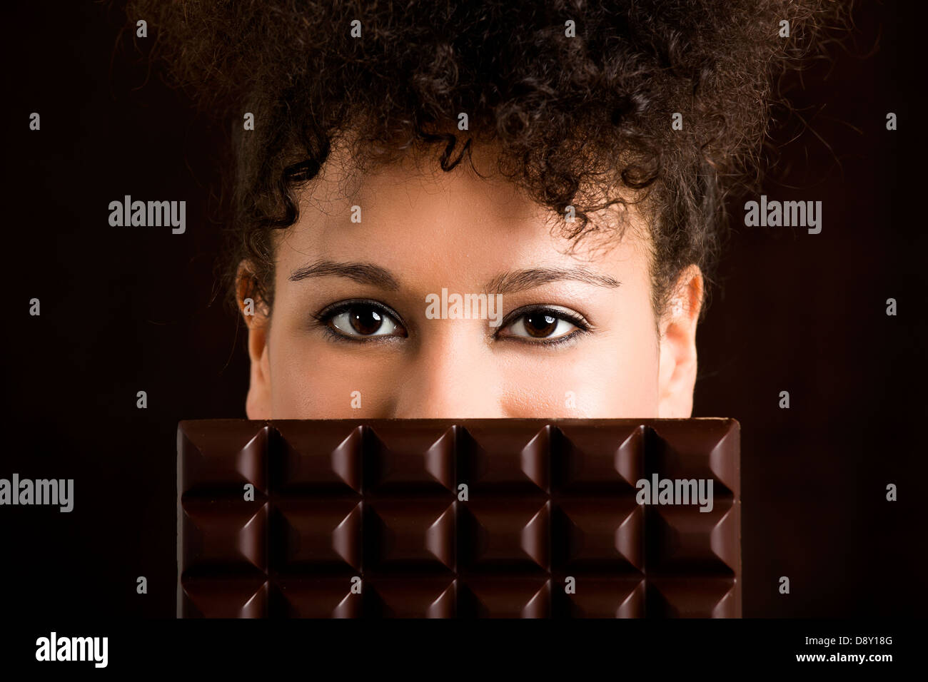 Bella donna africana tenendo un enorme dark chocolate bar Foto Stock