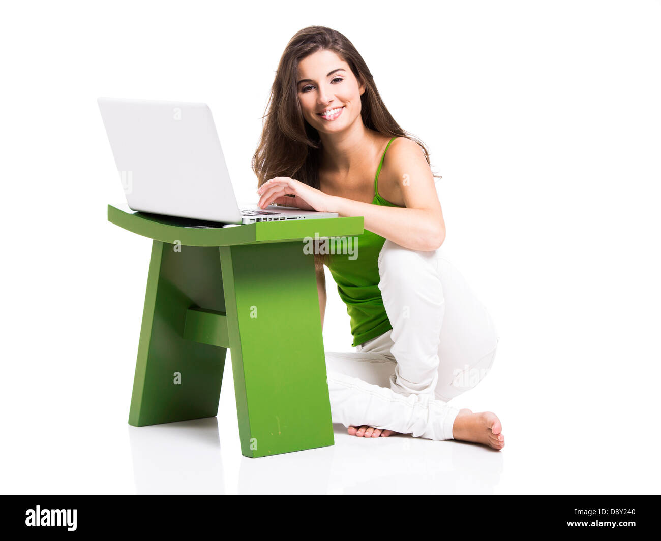 Bella donna seduta sul pavimento a lavorare con un computer portatile, isolate su un bianco Foto Stock