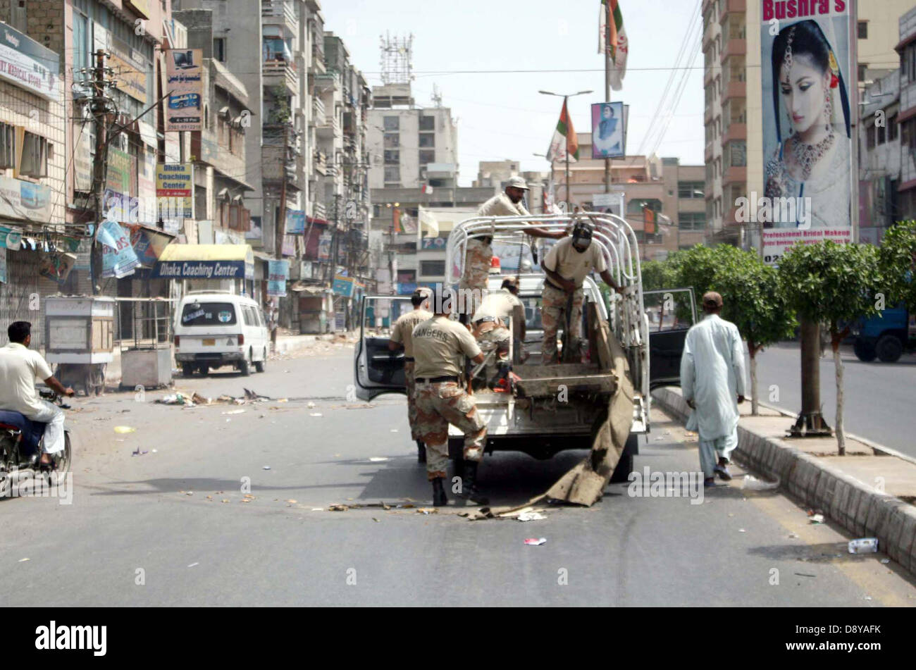 Rangers funzionari la rimozione di ostacoli che posto sulla strada durante uno sciopero nel collegamento di piangere giorno chiamato dalla Muttahida Qaumi Movement (MQM) contro bersaglio di uccisione di MQM attivisti e sostenitori, in Shah Faisal Colony n. 02 area di Karachi, giovedì 06 giugno, 2013. Foto Stock