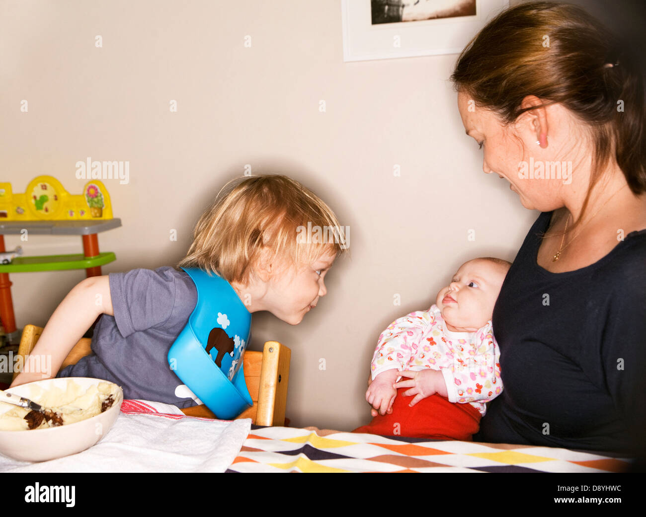 Una madre con due bambini da una tabella. Foto Stock