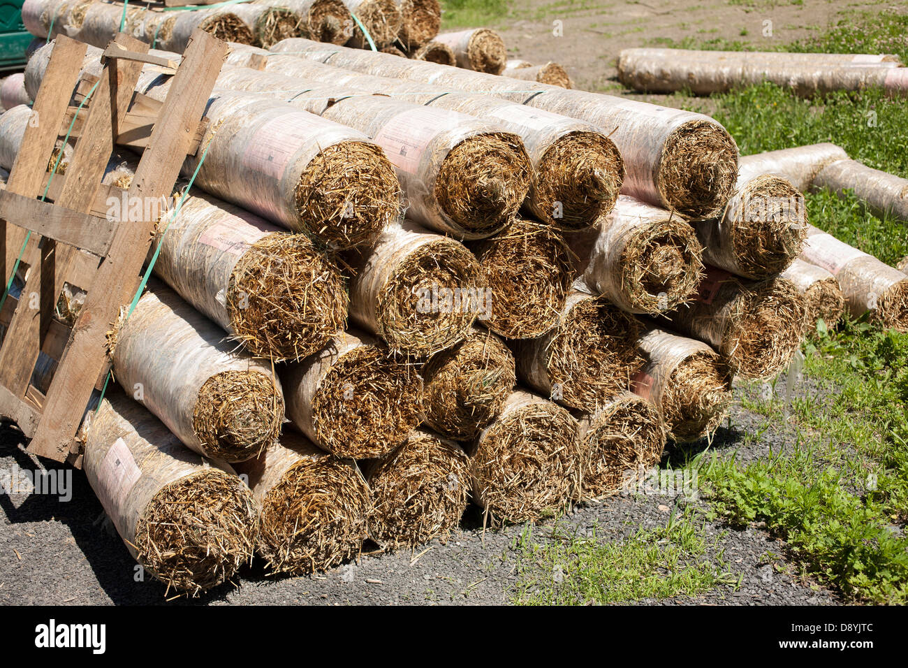 La paglia erosione controllo coperte sono arrotolati, in attesa di essere diffuso sul sito in costruzione a ridurre erosione prima di erba cresce Foto Stock