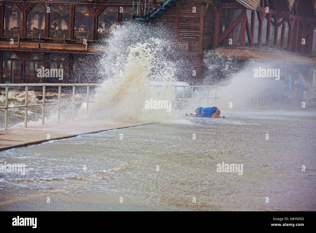 Storm Chaser Jim Edds accovacciato mentre le riprese lungo il Seawall nel centro cittadino di Cedar Key Florida durante la tempesta tropicale Andrea Foto Stock