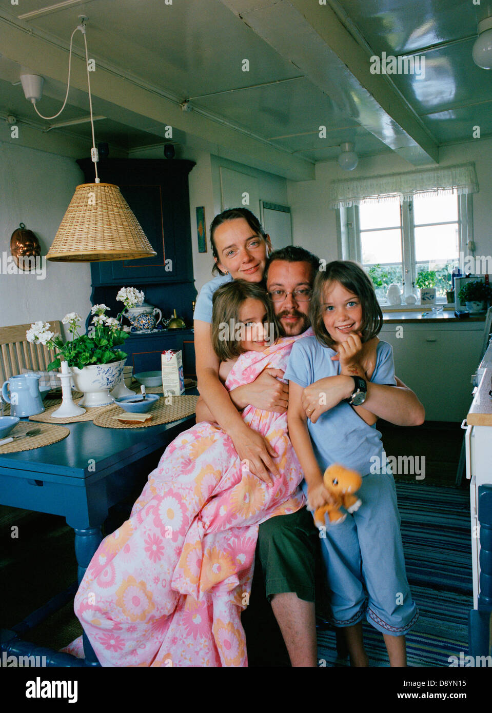 Famiglia con due figlia abbracciando all'interno di home Foto Stock