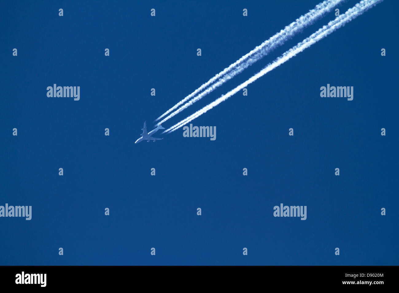 Jet aereo contro un cielo blu con contrails. Foto Stock