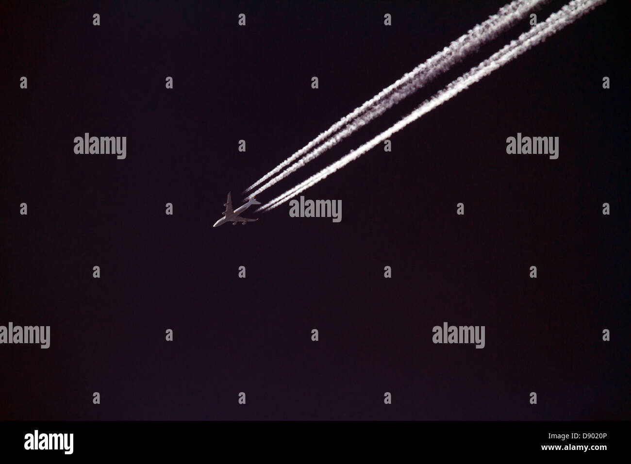 Jet aereo contro un cielo nero con contrails. Foto Stock