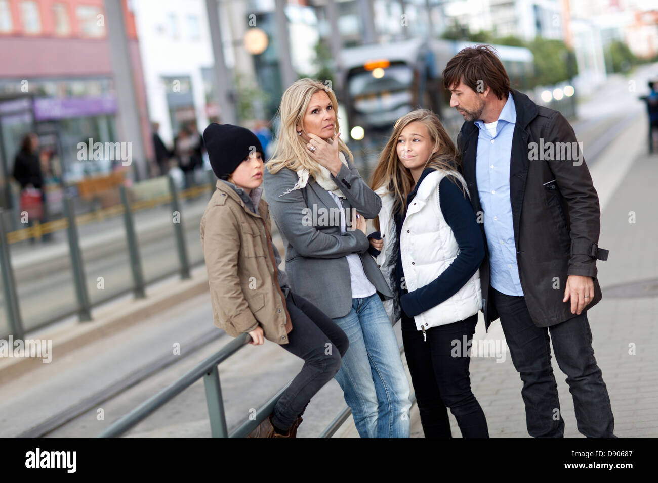 Famiglia con due bambini in attesa di tram Foto Stock