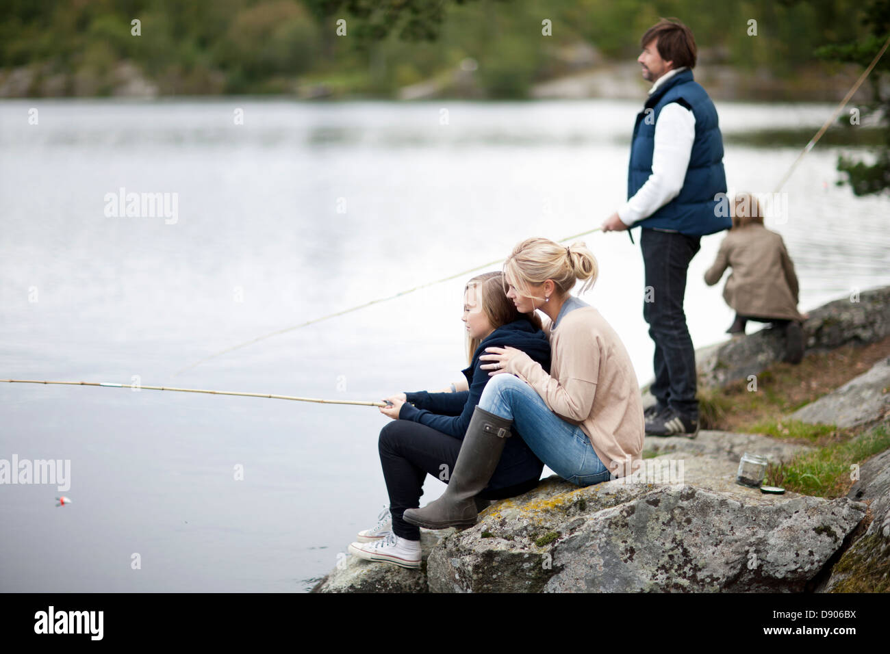 Famiglia con due bambini la pesca sul lago Foto Stock