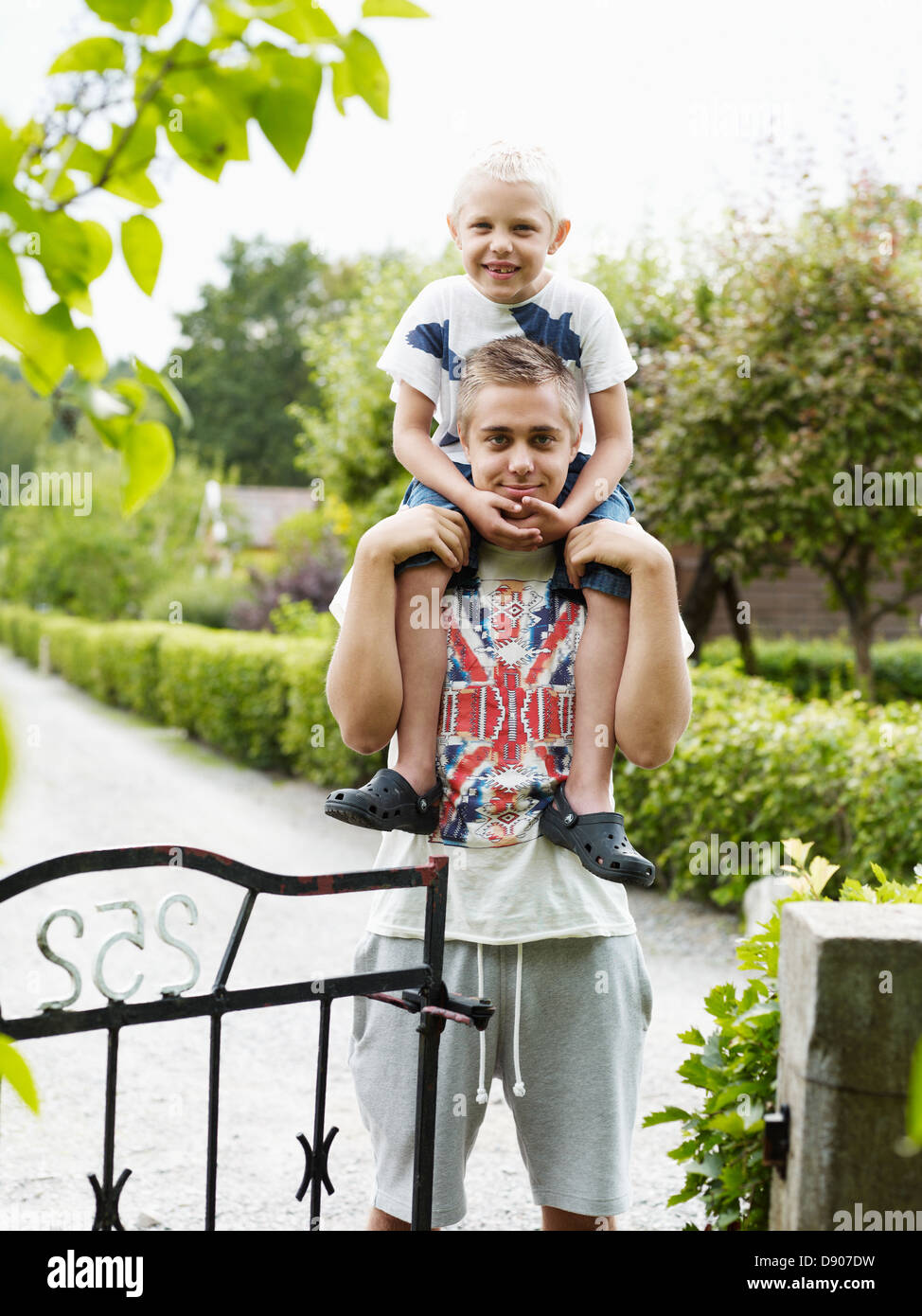 Ragazzo adolescente che trasportano il fratello minore sulle spalle Foto Stock