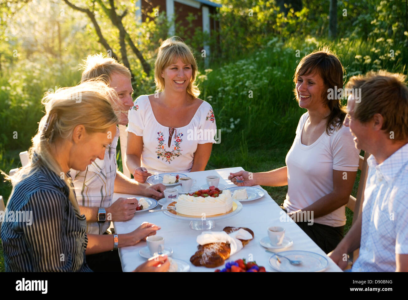 Cinque amici avente una torta durante la festa di mezza estate, arcipelago di Stoccolma, Svezia. Foto Stock