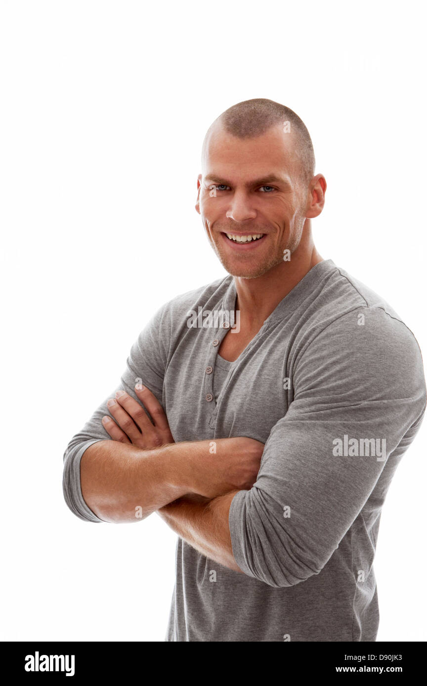 Giovane uomo in piedi con le braccia incrociate e sorridente Foto Stock