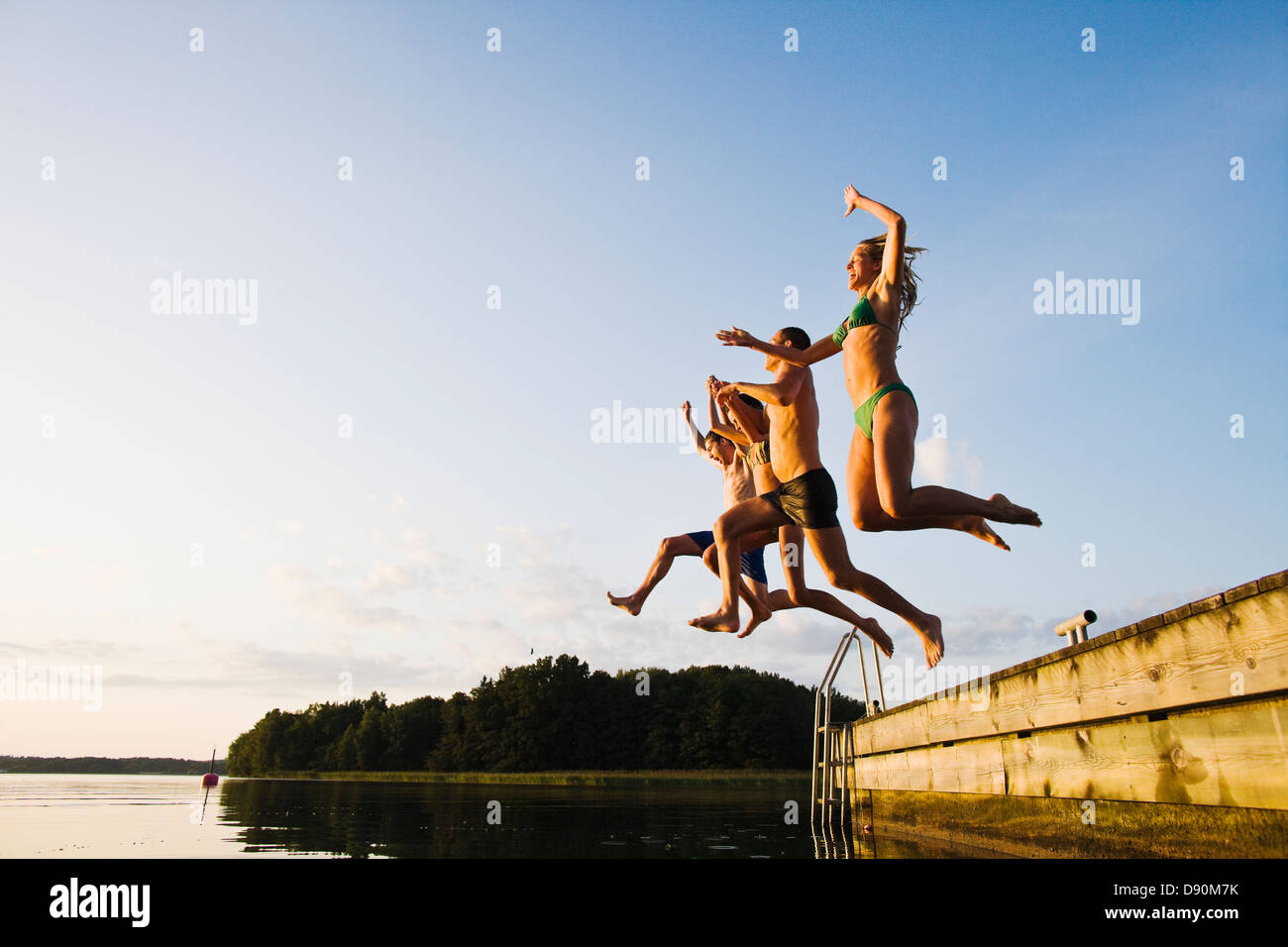 Amici saltando nel lago Foto Stock