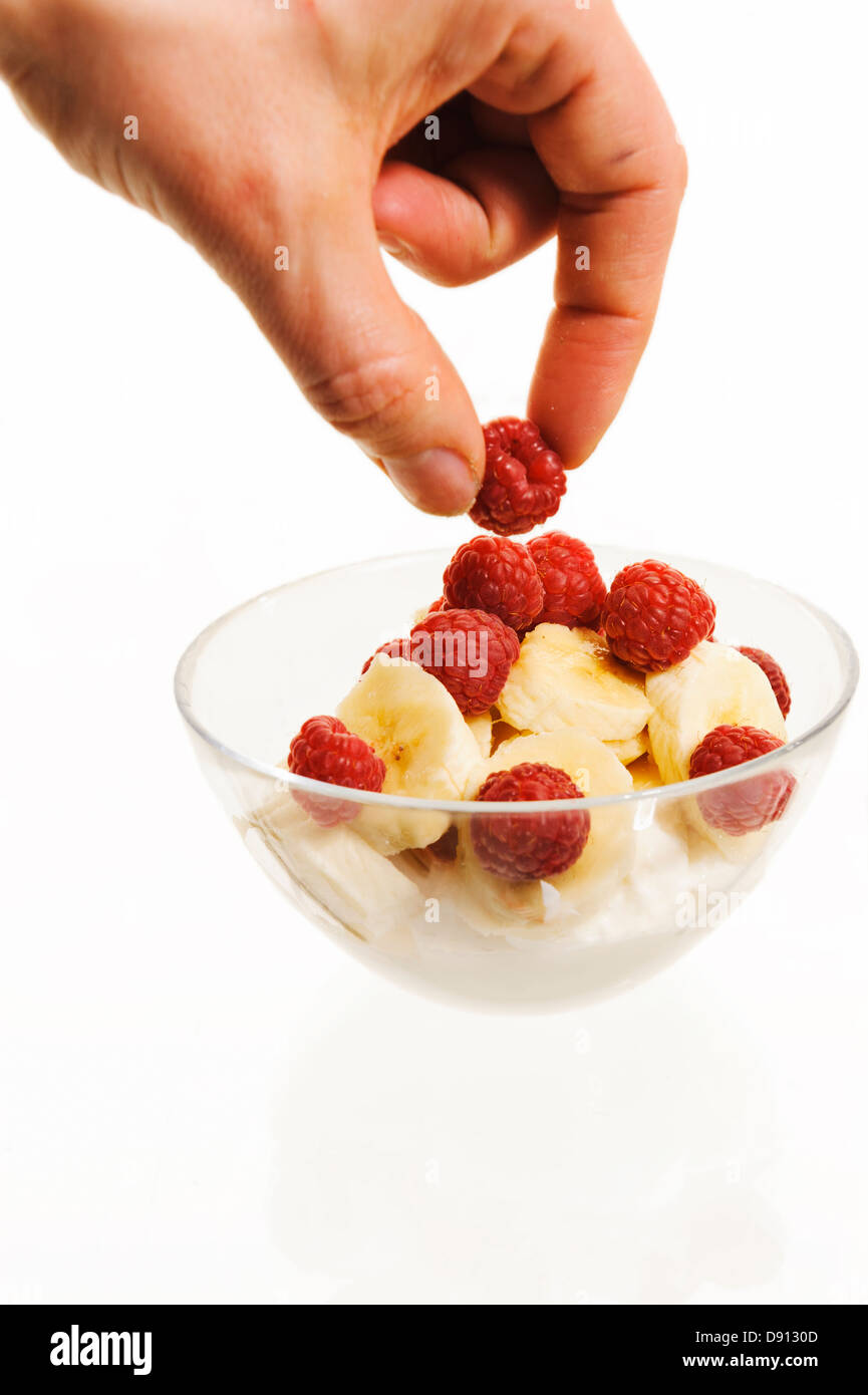 Mano azienda lampone sulla ciotola con lamponi e banane Foto Stock