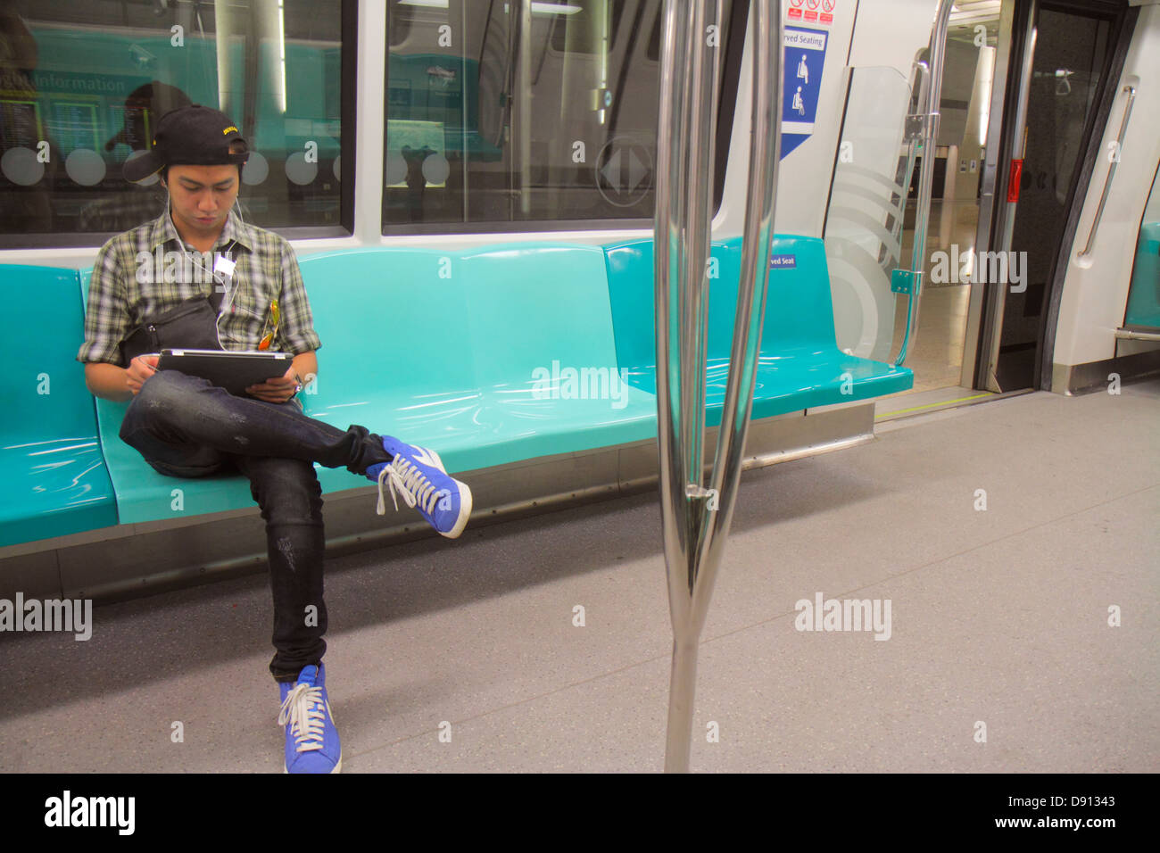 Singapore SMRT,East West Green Line,trasporto rapido di massa,cabina passeggeri,uomo asiatico uomo maschio,passeggeri passeggeri riders riders,riders,sitting,laptop,noteb Foto Stock