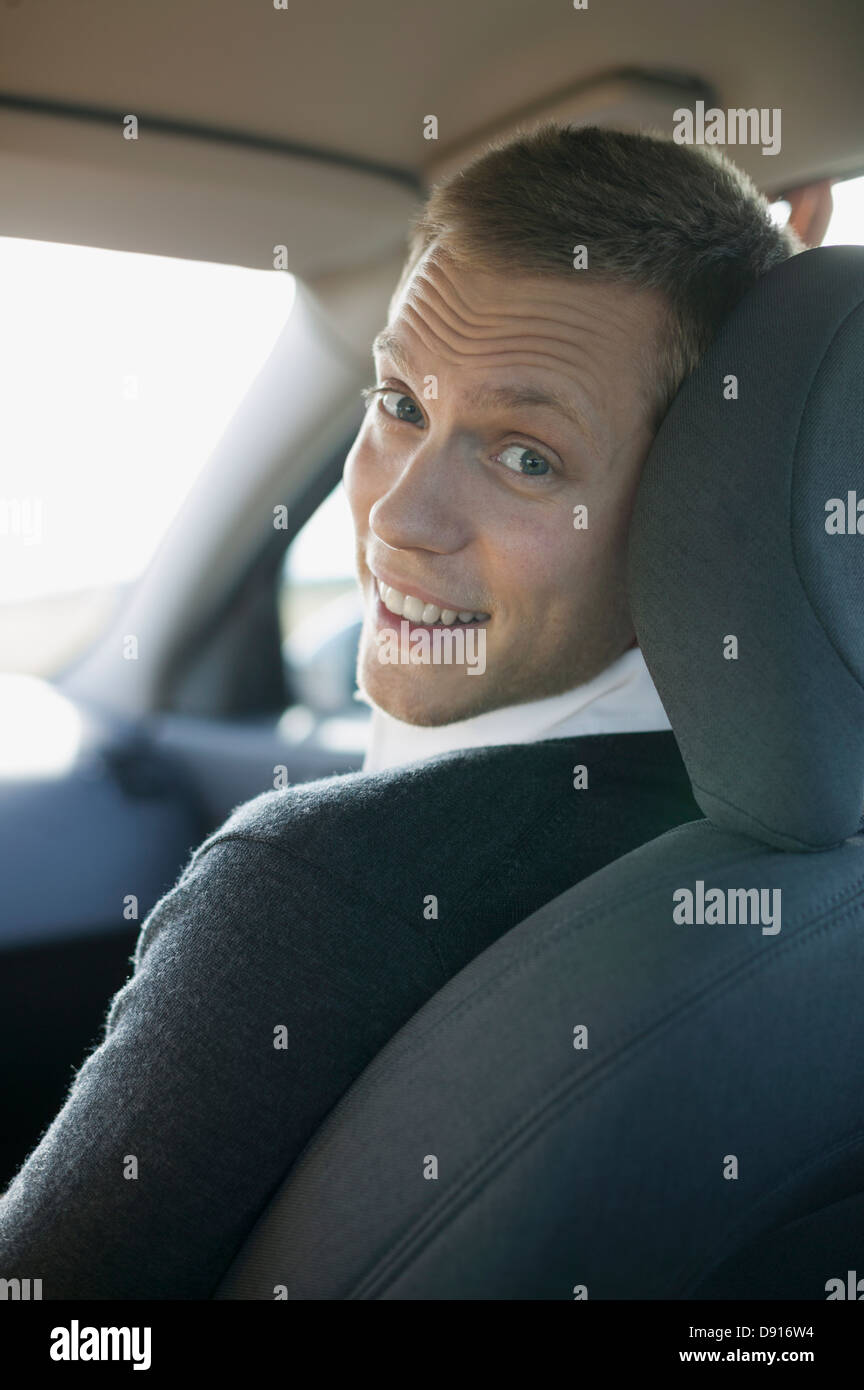 Uomo sorridente seduto in macchina e guardando la fotocamera Foto Stock