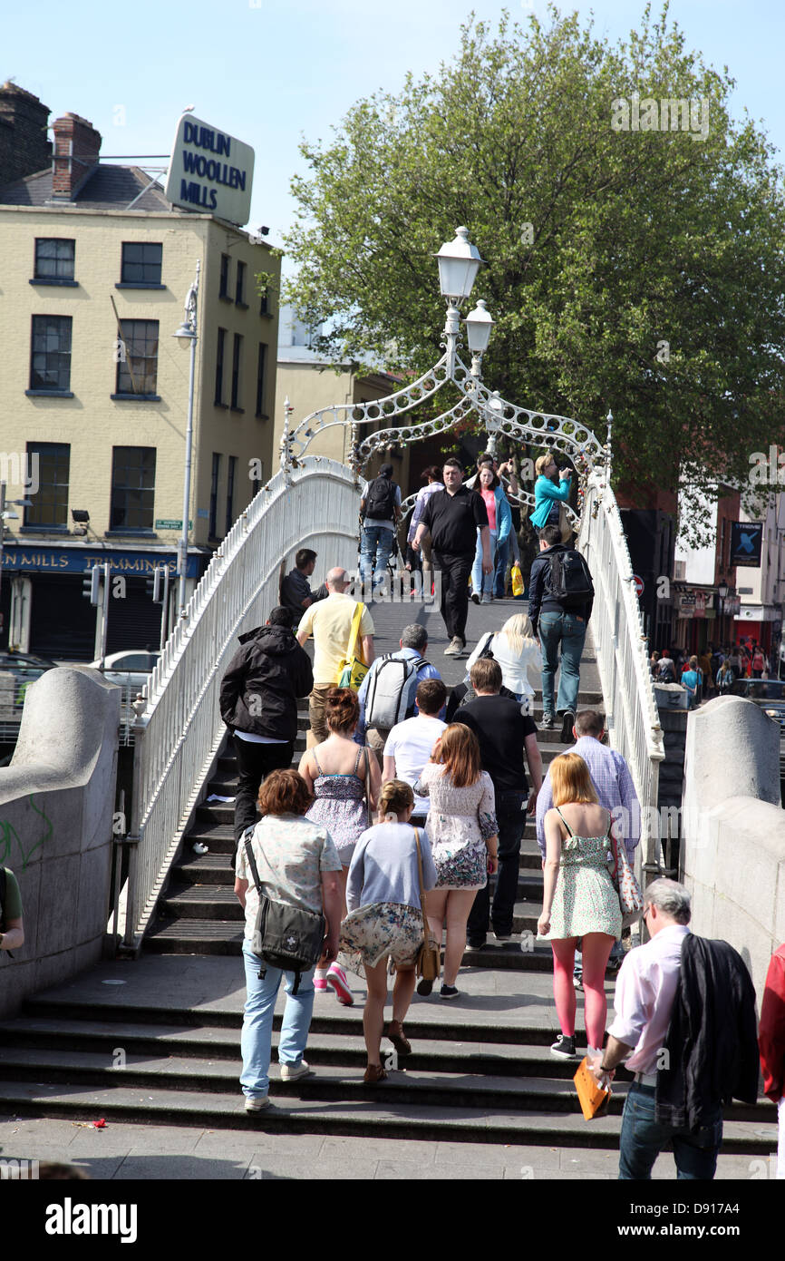 Folla attraversando Halfpenny ponte sopra il fiume Liffey, Dublino Foto Stock