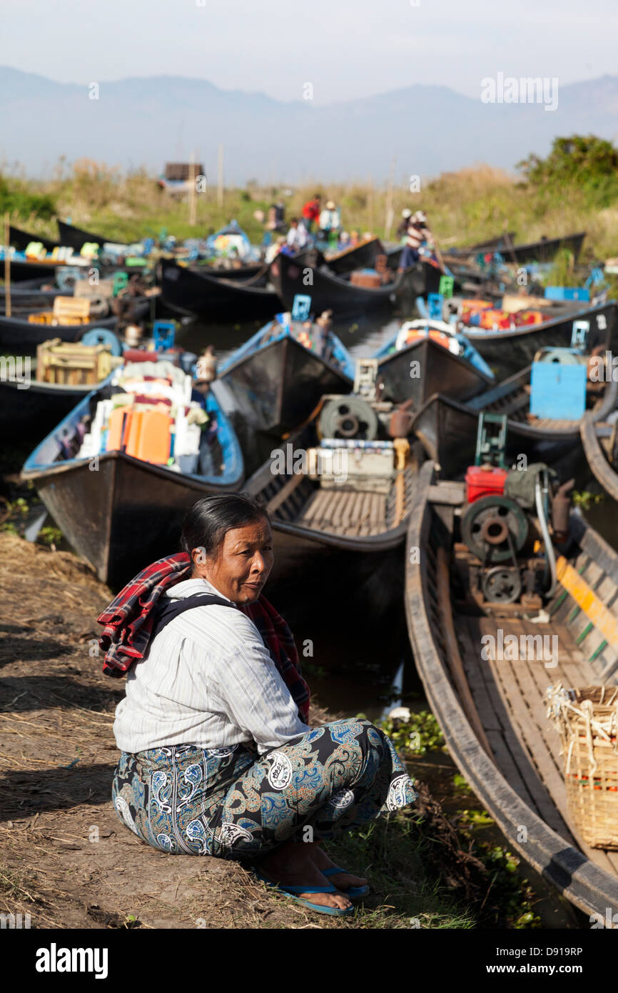 Il vecchio donna seduta da barche in un piccolo villaggio sul Lago Inle, Myanmar Foto Stock