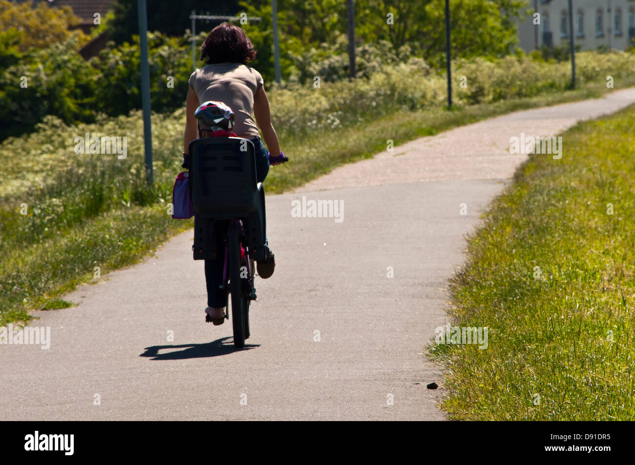 Madre donna in bici con il bambino in bicicletta seggiolino per bambini Foto Stock