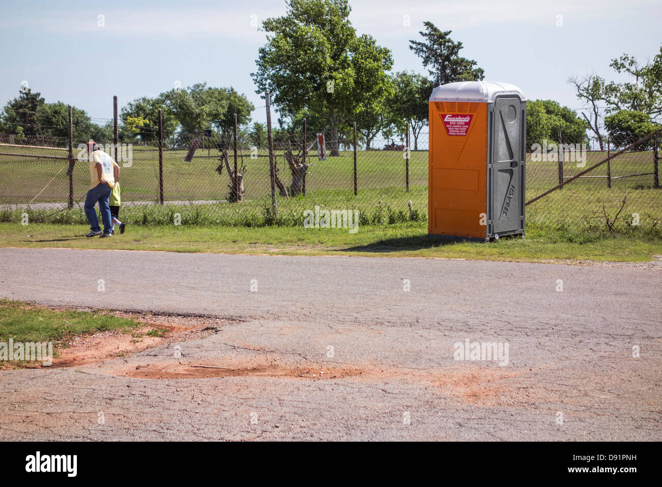 Un uomo ispanico e il suo piccolo ragazzo a piedi dopo usando un bagno portatile al Lago Hefner, Oklahoma City, Oklahoma, Stati Uniti d'America. Foto Stock