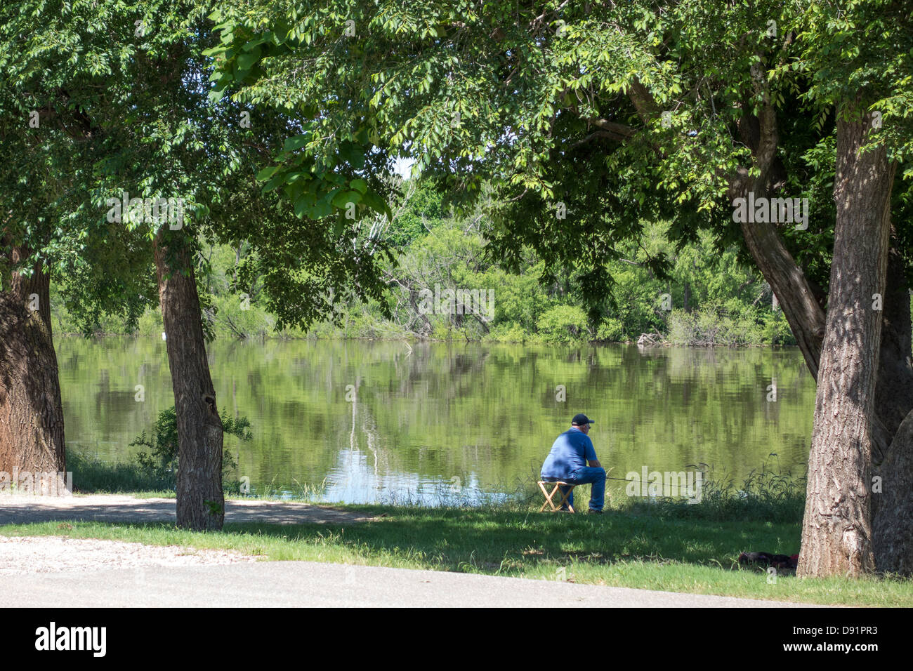 Un senior caucasica uomo si siede su uno sgabello e i pesci al Lago Hefner nella città di Oklahoma, Oklahoma. Stati Uniti d'America Foto Stock