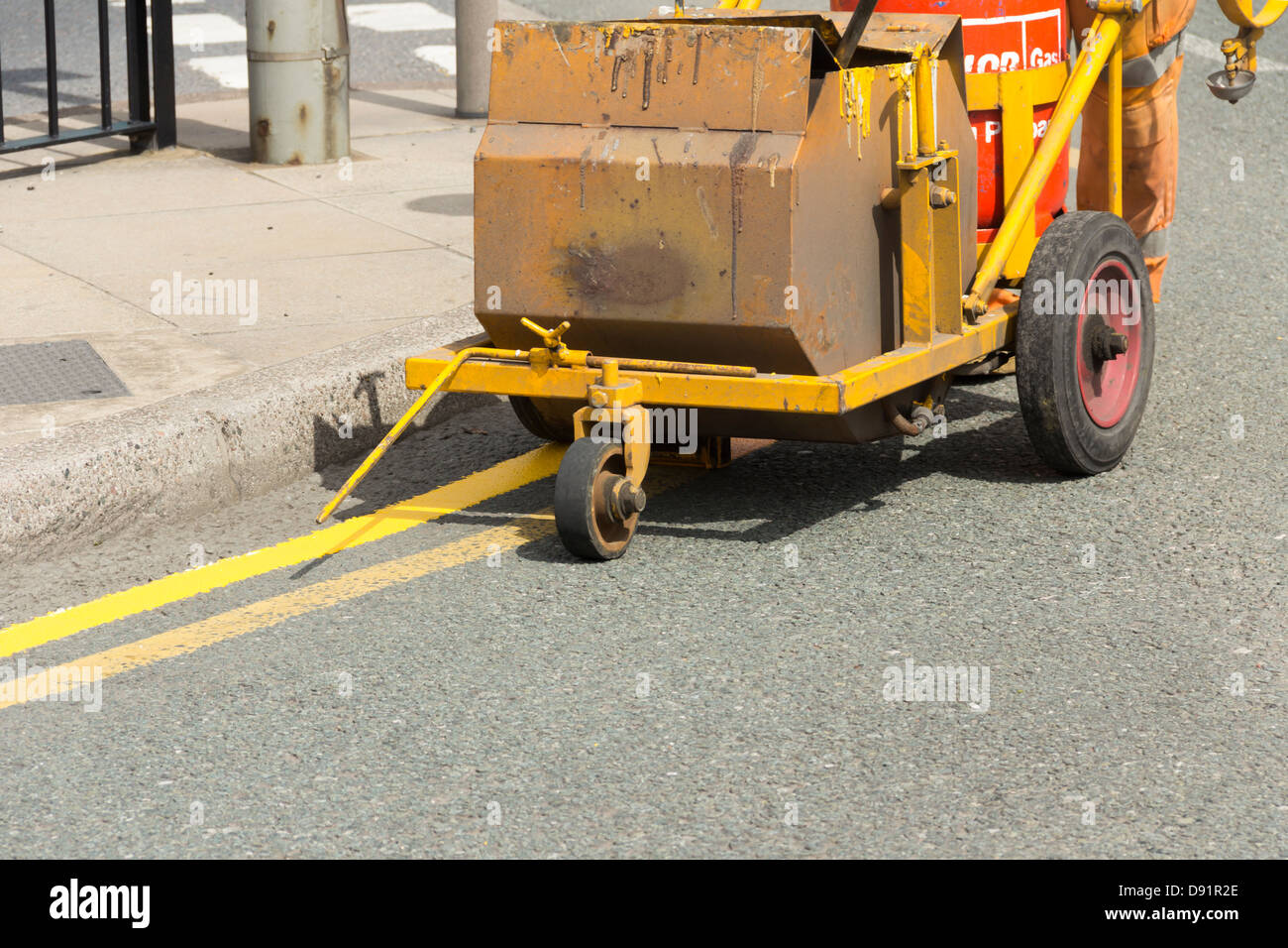 Doppia linea gialla pittura in corso. Un Calor Gas riscaldatore mantiene la vernice termoplastica liquido fino a quando applicato. Foto Stock