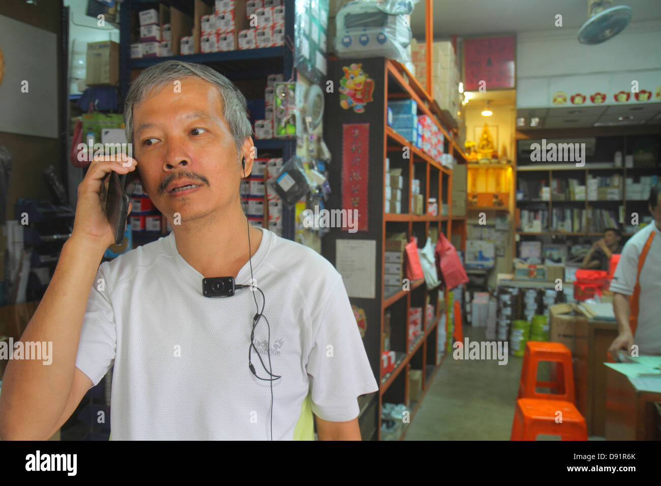 Singapore,Jalan Besar,illuminazione,lampadina,fornitore,ufficio,uomo asiatico maschio,telefono,smart phone,telefoni,controllo cercando di leggere messaggi di testo, m Foto Stock