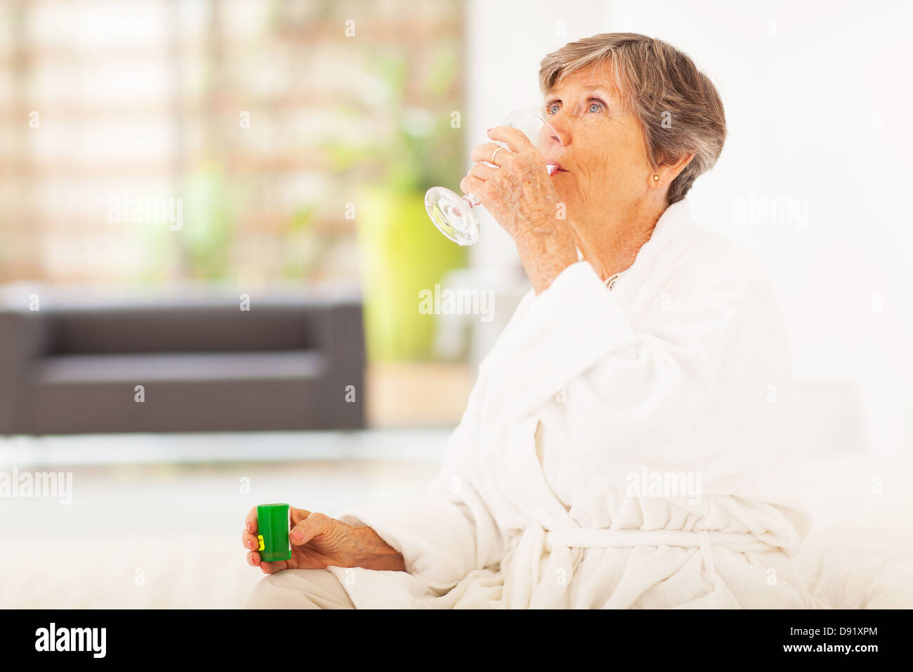 Donna anziana medicina da bere a casa Foto Stock