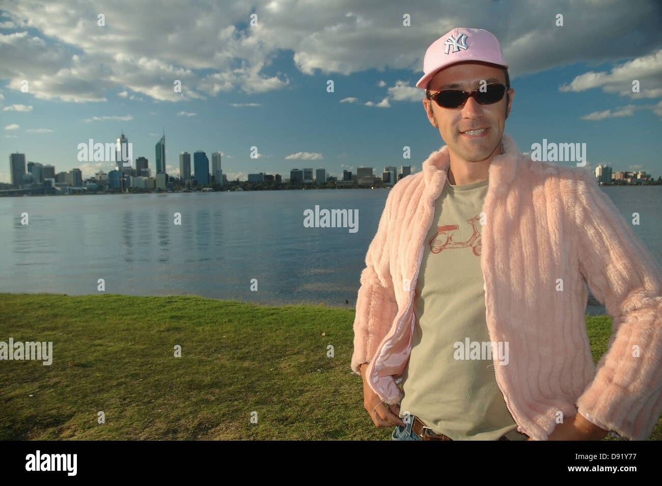 Giovane uomo in rosa con lo skyline della città in background Foto Stock
