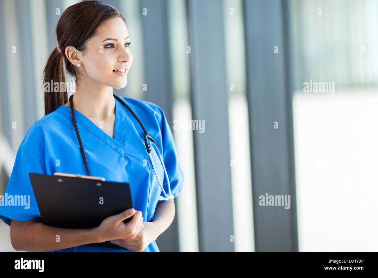 Bella giovane femmina medico internista guardando fuori dalla finestra Foto Stock