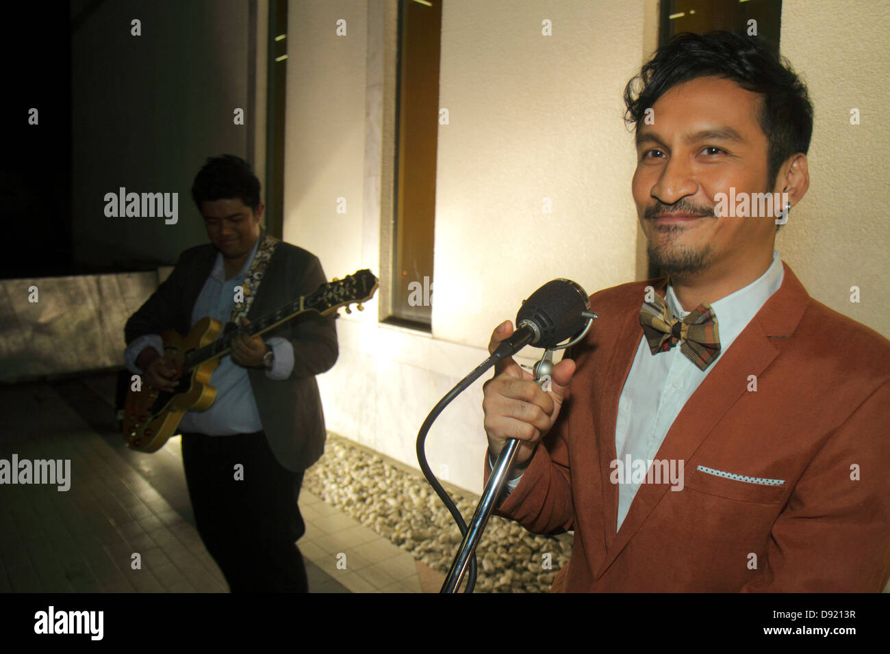 Bangkok Thailandia,Thai,Pathum WAN,Rama 1 Road,strada,marciapiede,strada,musicisti,esibizione,uomo asiatico maschio,serata notturna,cantante,microfono,band,Thai1 Foto Stock