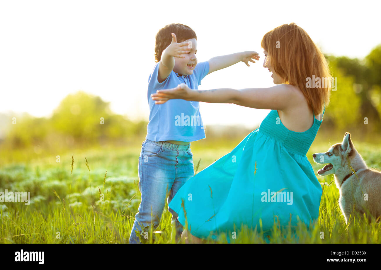 Madre con suo figlio e il loro cane plaing nel campo verde,l'estate Foto Stock