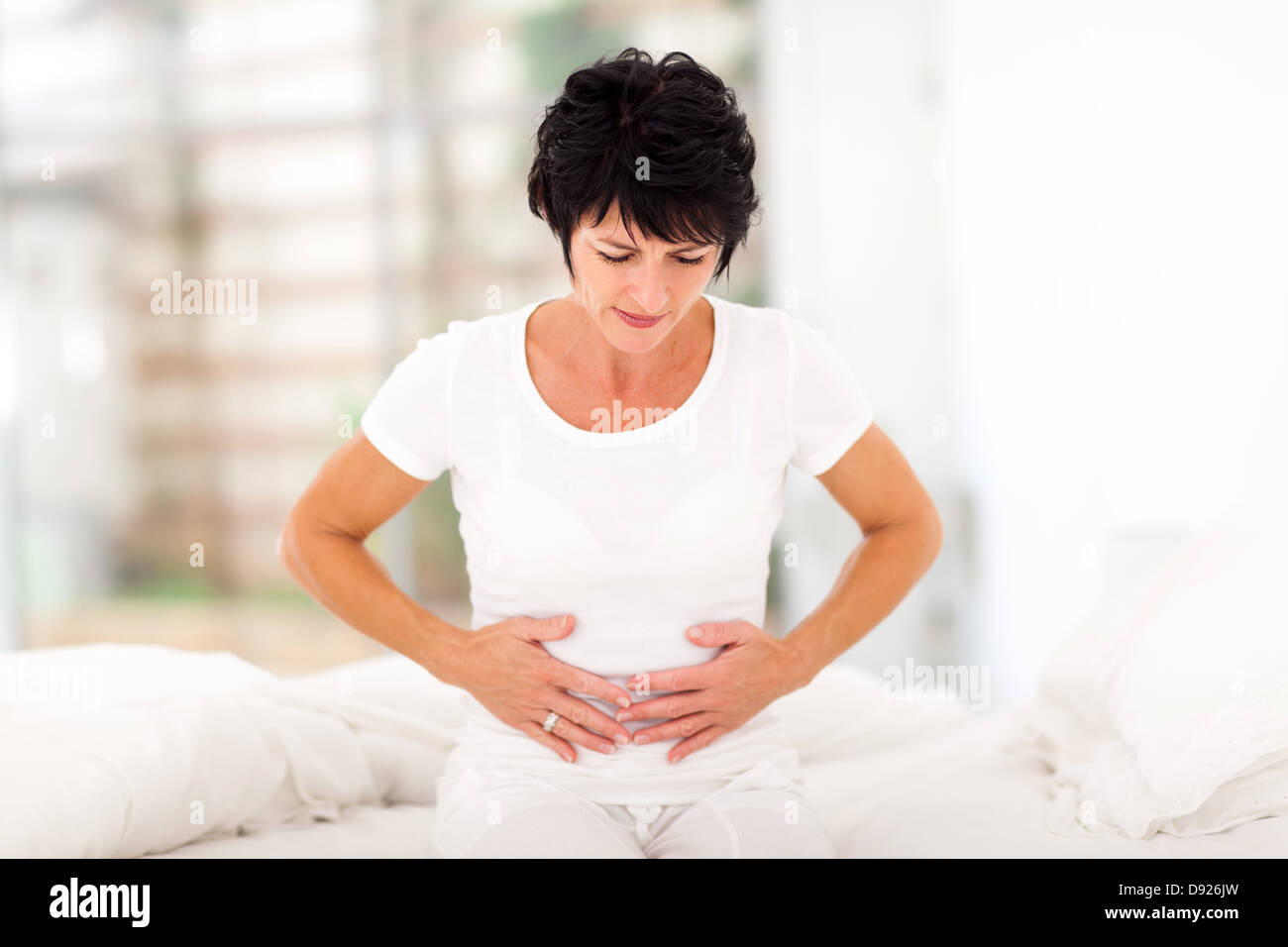 Età media donna con dolore di stomaco a casa Foto Stock