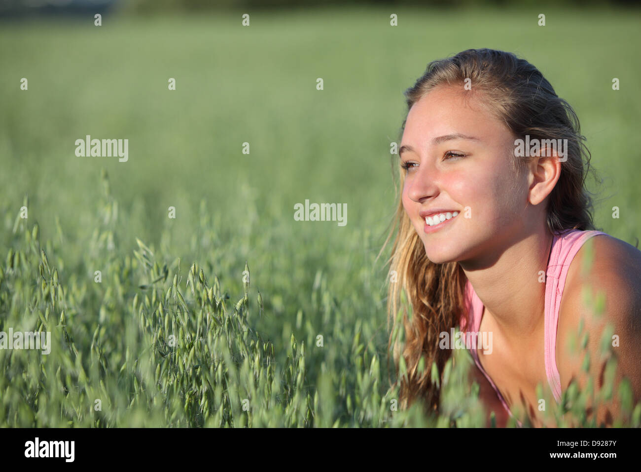 Primo piano di una bella ragazza adolescente sorridente in un unfocused verde prato di avena Foto Stock