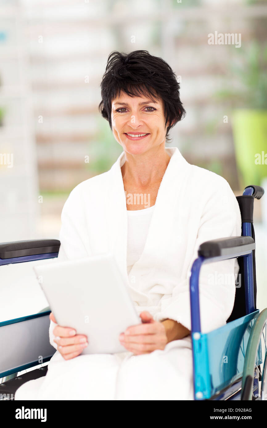 Portatori di handicap donna di mezza età con tablet pc a casa Foto Stock