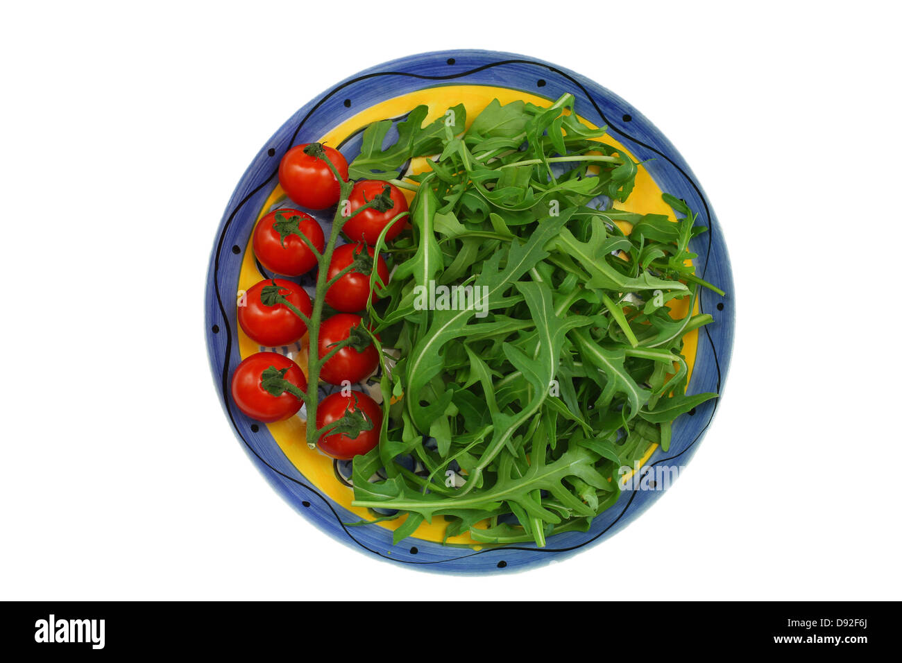 Foglie di Rucola e Pomodori ciliegia sulla piastra vintage isolato su bianco Foto Stock