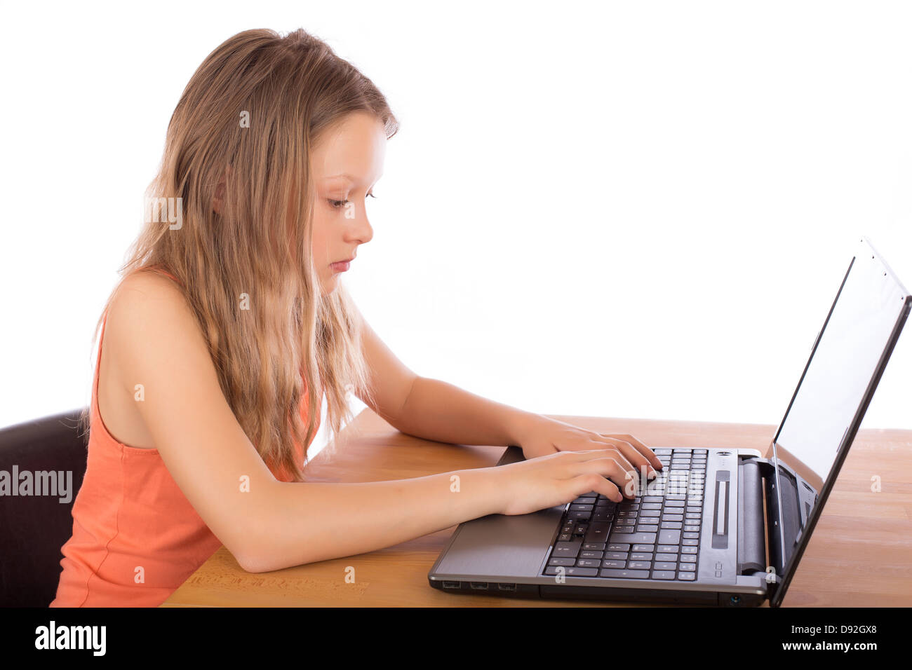 Piuttosto giovane ragazza con i capelli lunghi e t-shirt lavorare seriamente su un laptop. Isolato su sfondo bianco. Foto Stock