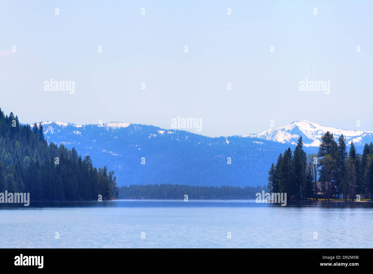 Teleobiettivo con vista del lago Payette e cime ricoperte di neve contro azzurro cielo da estremità nord del lago fuori McCall, Idaho Foto Stock