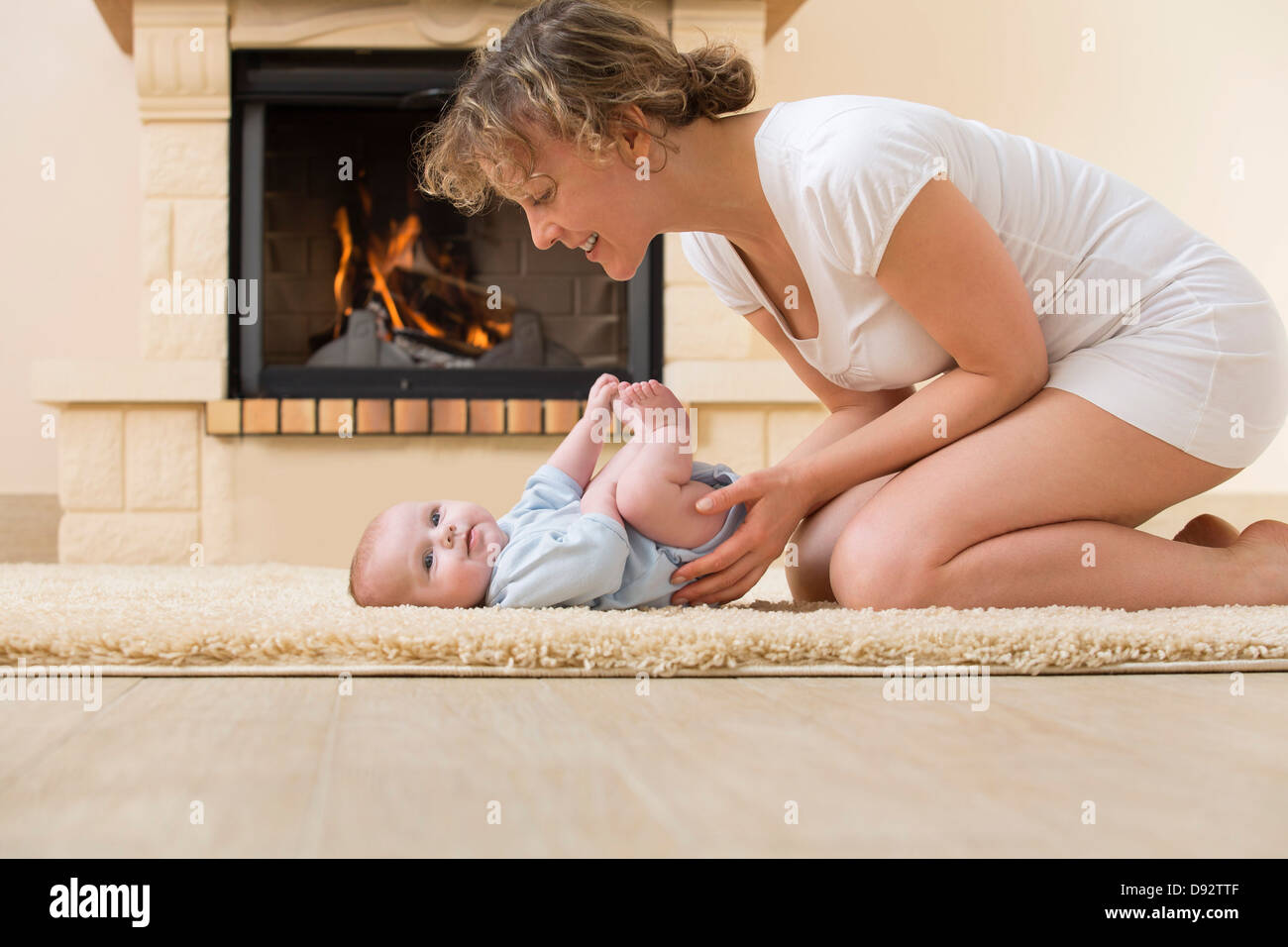 Madre e figlia sul tappeto davanti al fuoco Foto Stock