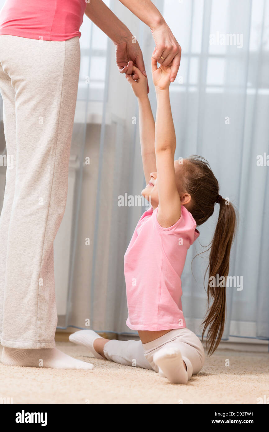 Ragazza facendo la divide con un po' di aiuto da parte di sua madre Foto Stock