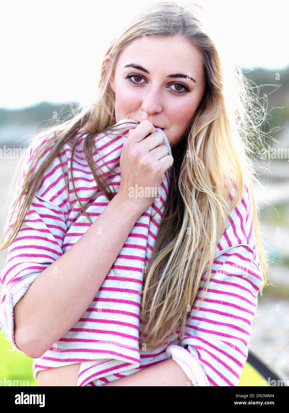Una giovane donna che copre la bocca con la sua camicia e sorridendo scherzosamente Foto Stock