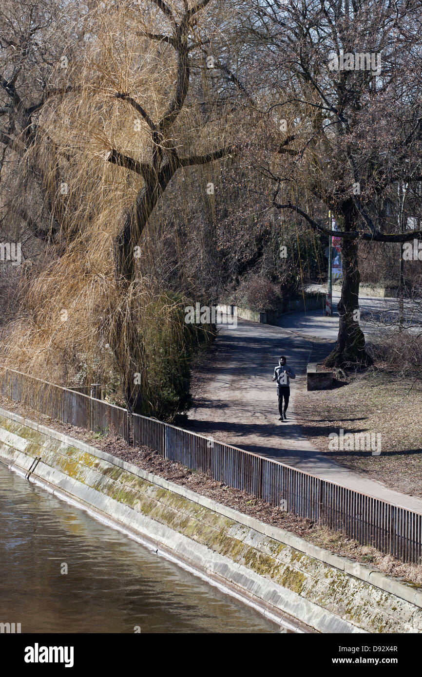 Un giovane uomo jogging attraverso un parco cittadino Foto Stock