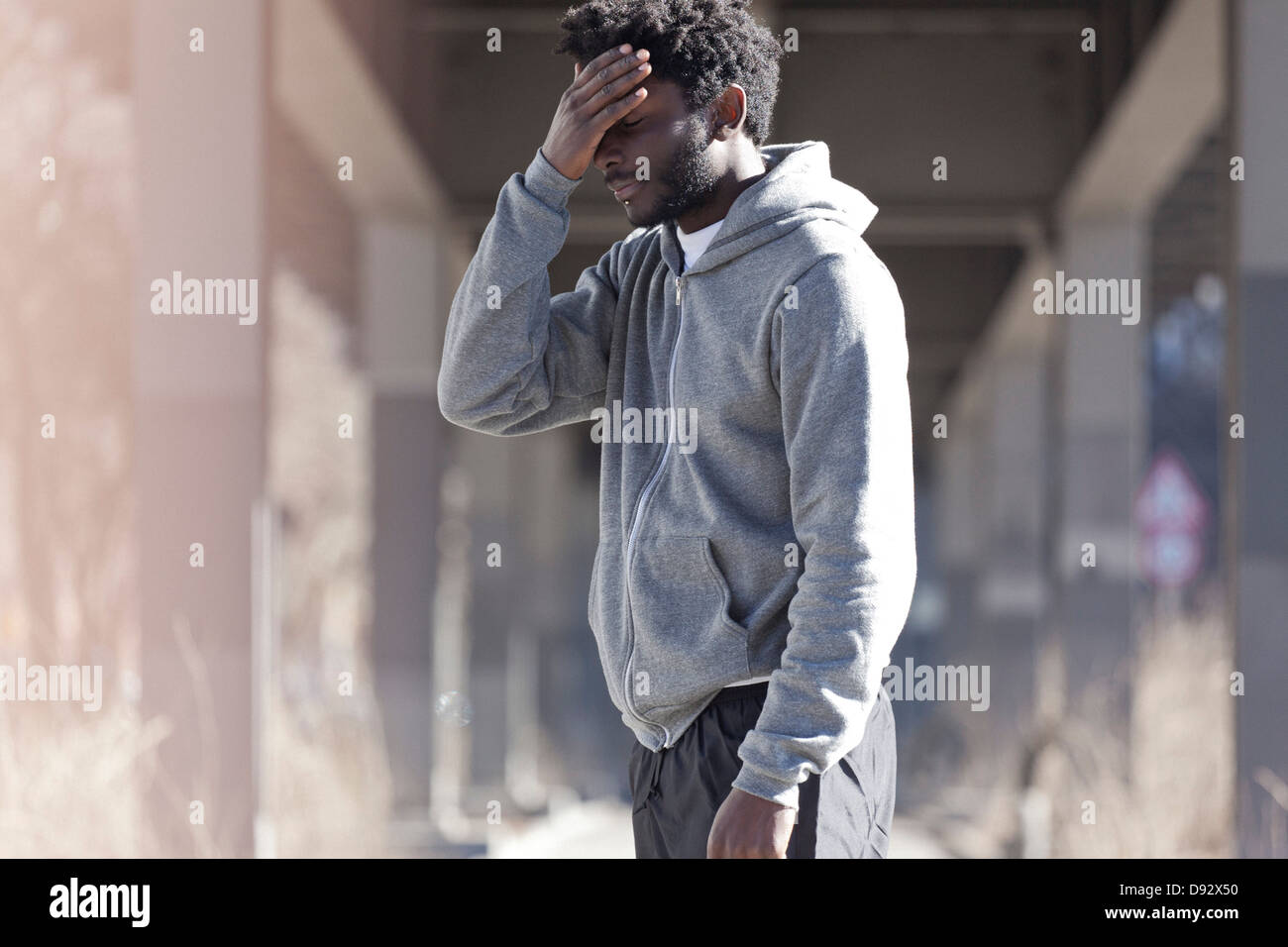 Un uomo con la sua mano sulla sua fronte con un look di deiezioni Foto Stock