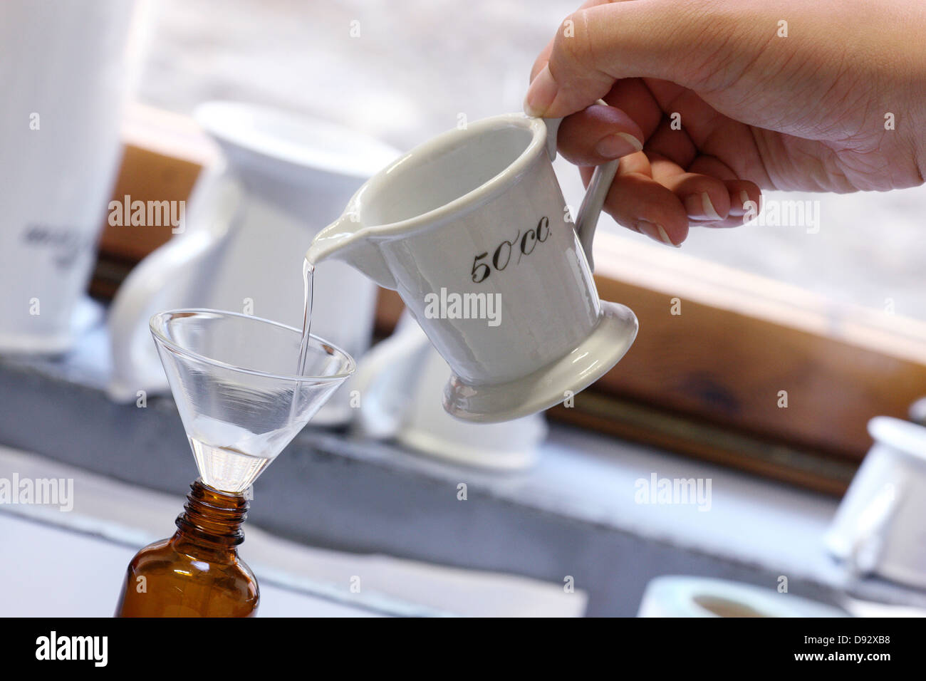 Un farmacista versando una medicina liquida in un flaconcino attraverso un imbuto Foto Stock