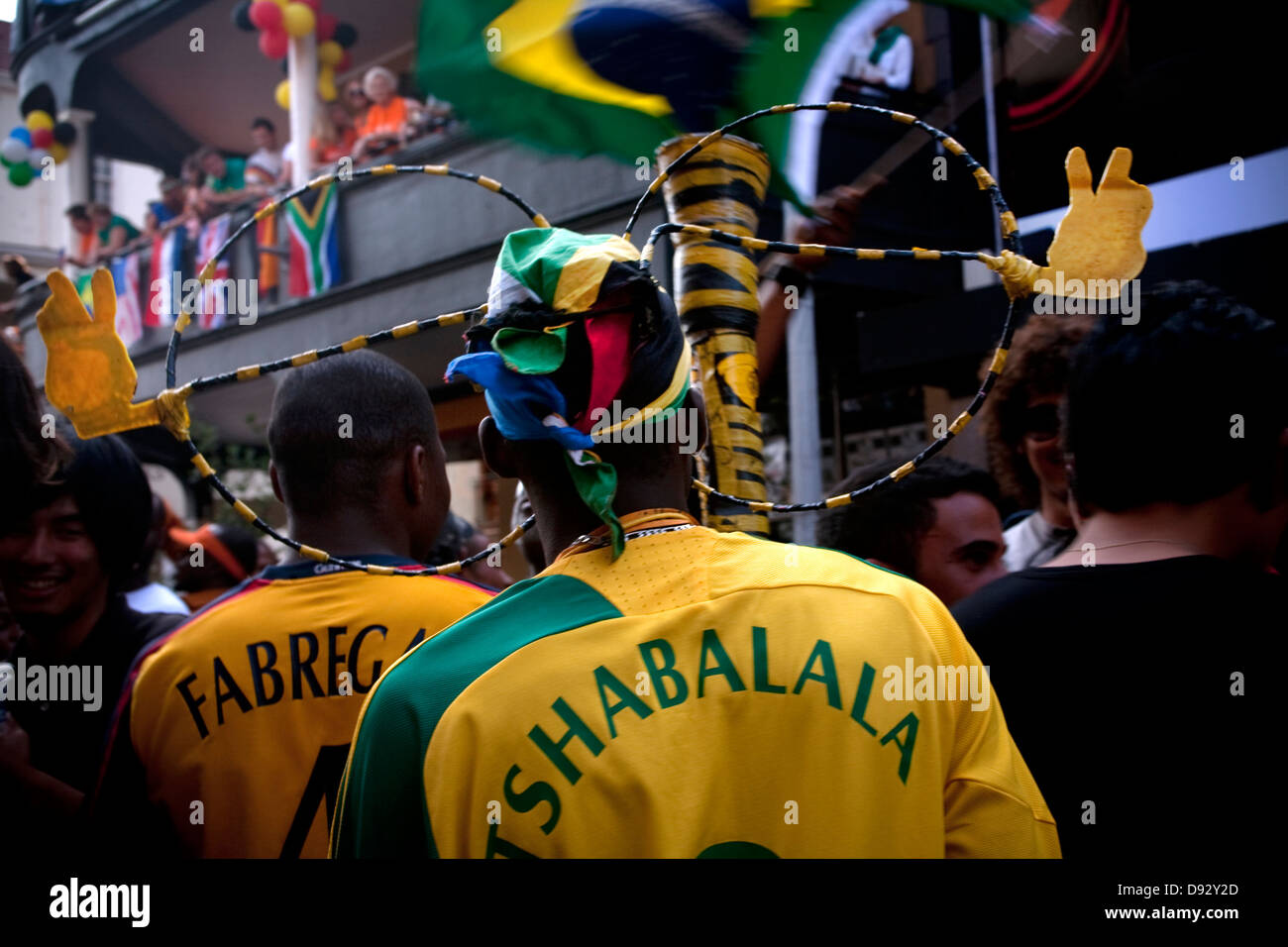 Appassionato di calcio in Tshabalala football shirt detiene vuvazela indossa occhiali oversize durante estrazione finale per la coppa del mondo FIFA festeggiamenti Foto Stock