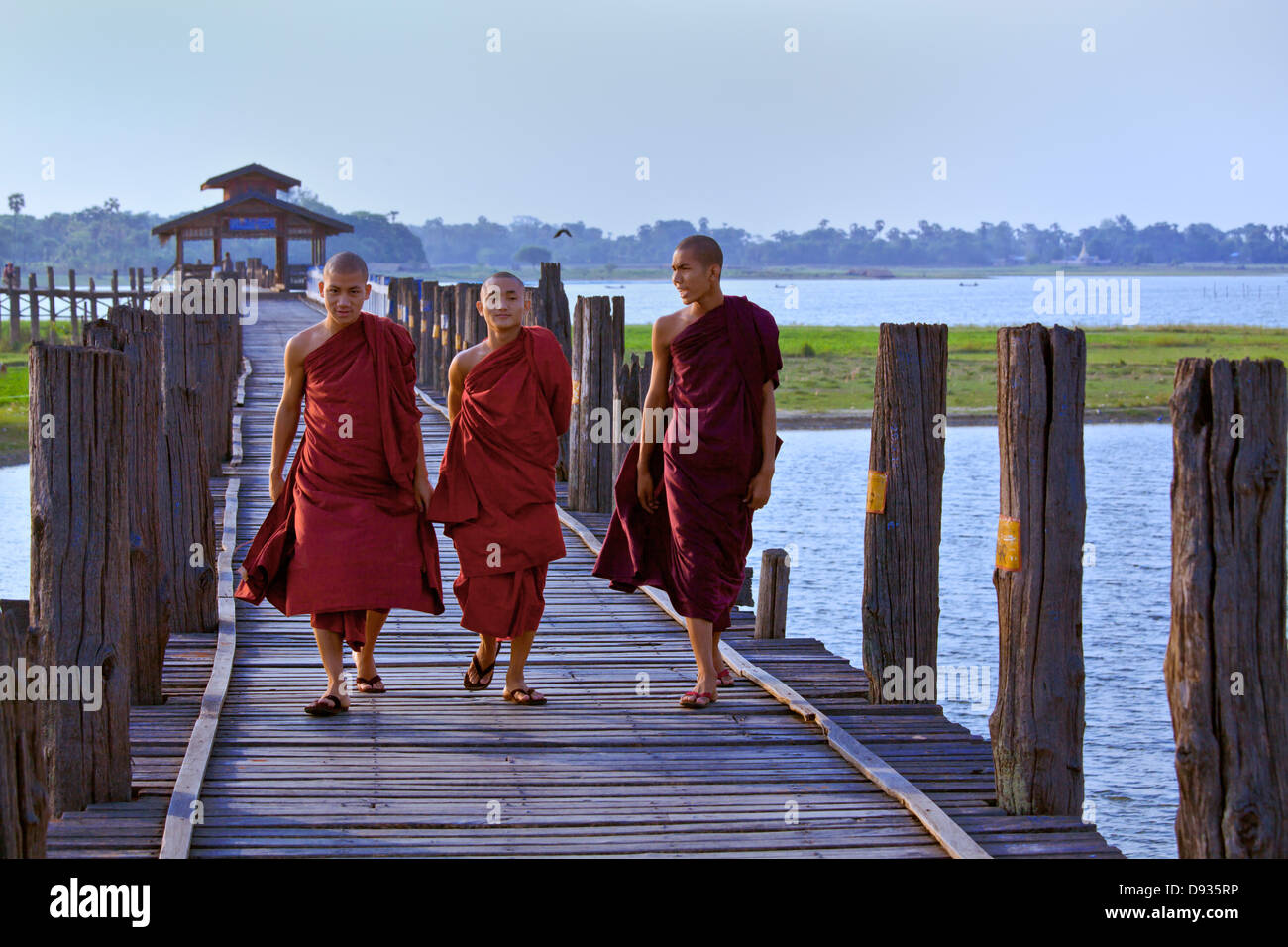 I MONACI BIRMANI utilizza il teak U BEINS ponte per commutare tra il Lago Taungthaman presso sunrise - AMARAPURA, MYANMAR Foto Stock