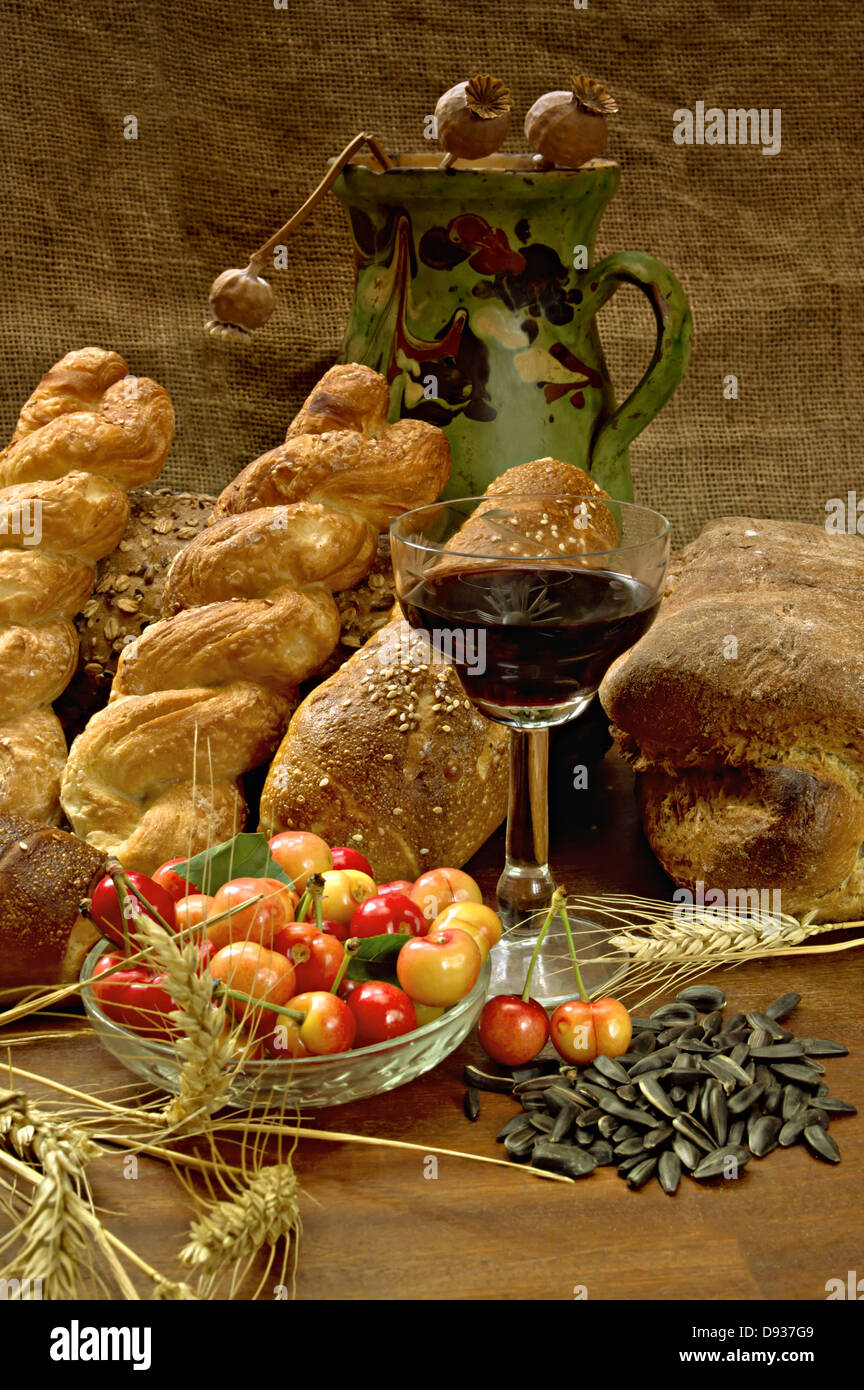Natura morta con pane, cherrys, e vino sul tavolo di legno. Foto Stock