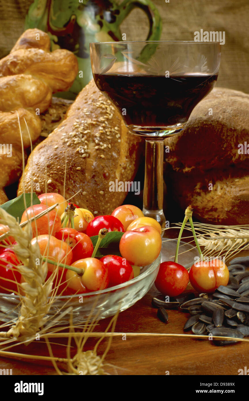 Natura morta con pane, cherrys, e vino sul tavolo di legno. Foto Stock