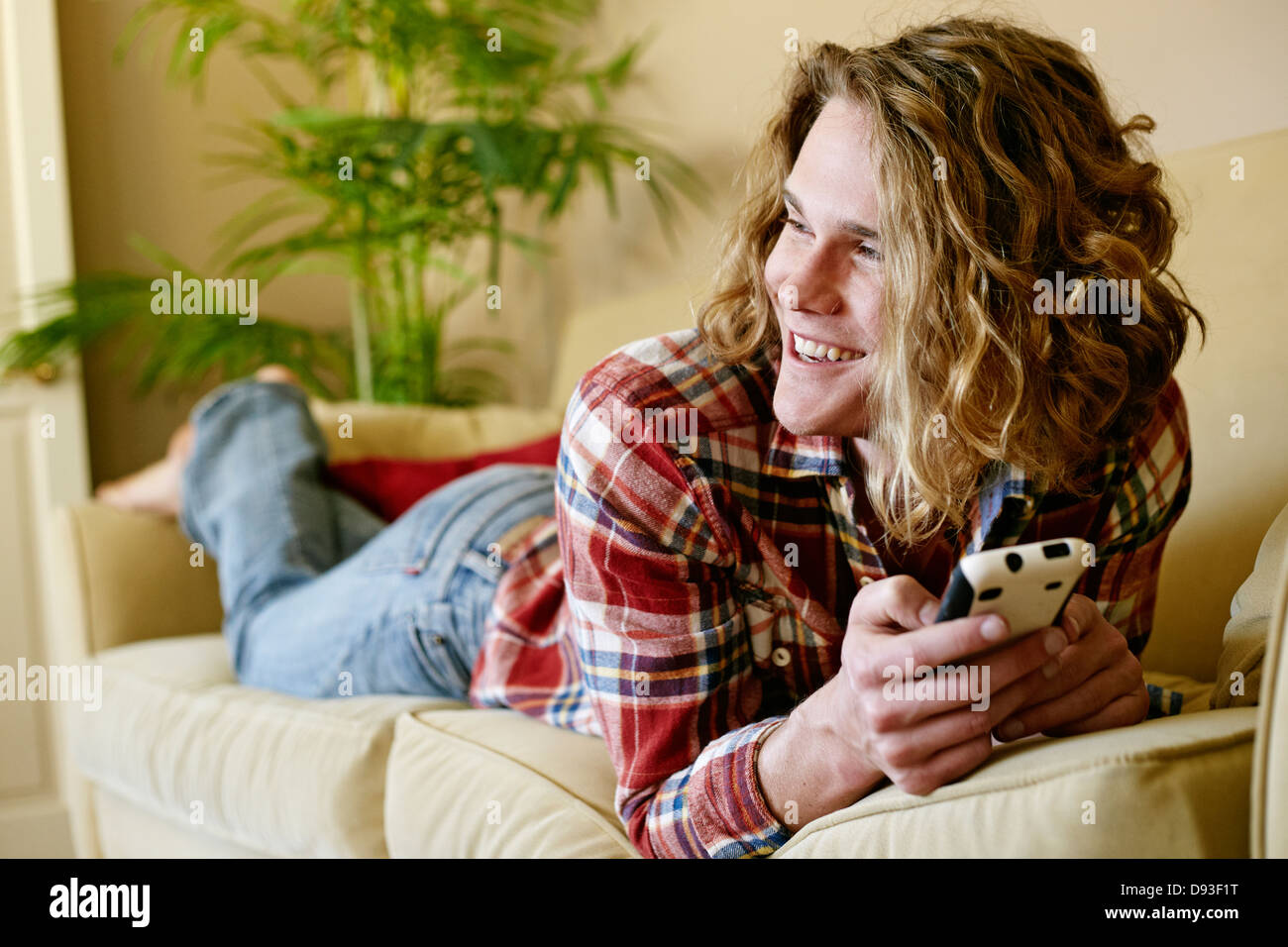 Uomo caucasico tramite telefono cellulare sul divano Foto Stock