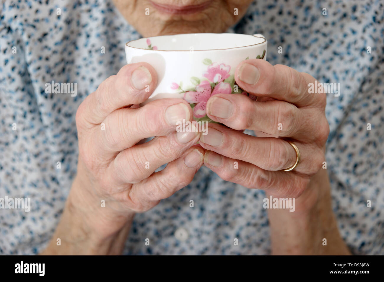 In prossimità di una donna anziana con le mani in mano tenendo una tazza o tazza di tè / caffè Foto Stock